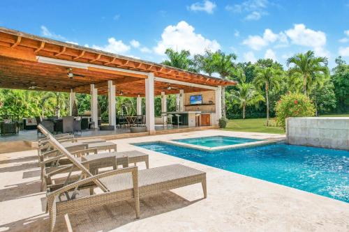 拉罗马纳Stunning Villa with Private Pool and Jacuzzi in Casa de Campo的一个带庭院和房子的游泳池