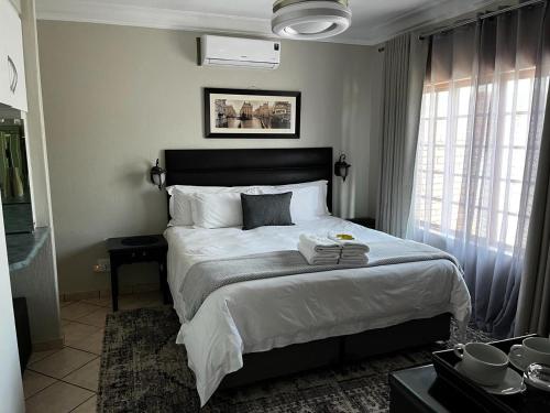 比勒陀利亚Klyne Jiweel Guesthouse的一间卧室配有一张带白色床单的大床