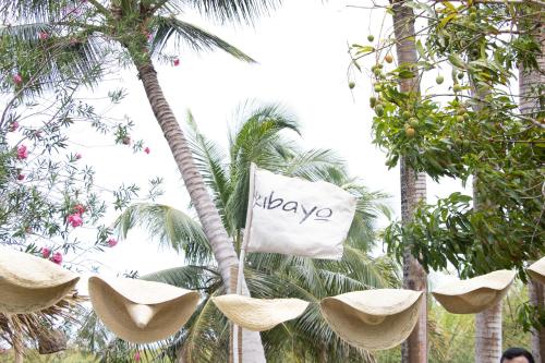 喀巴里特Kibayo Lagoon Villa的挂在棕榈树上并戴帽子的标志