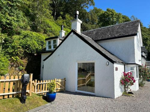 奥本Craigneuk near Oban, stunning home with sea views and EV hookup的一座白色的小建筑,设有大门和栅栏