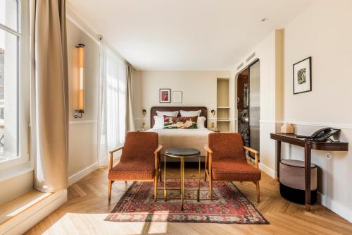 巴黎Hôtel Chamar的一间卧室配有一张床、两把椅子和一张桌子