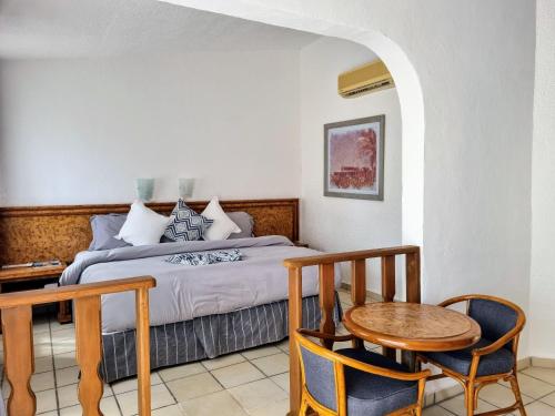 雪松山Buena Vista Oceanfront & Hot Springs Resort的卧室配有一张床和一张桌子及椅子