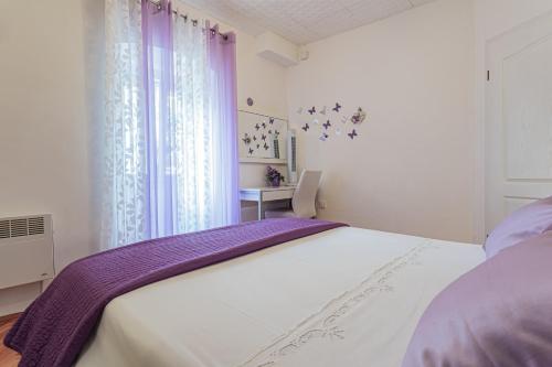 特罗吉尔Apartments & Rooms Trogir Stars FREE PARKING的一间卧室配有一张带紫色床单的大床和窗户。