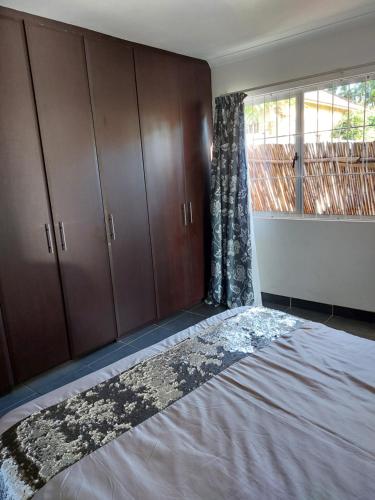 德班Morningview Cottage的一间卧室设有一张床、木制橱柜和窗户。