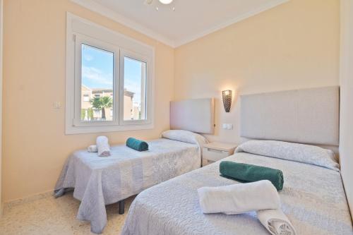 奥利瓦OLIVA NOVA GOLF BEACH & RESORT club sevilla IV 33A的客房设有两张床和窗户。