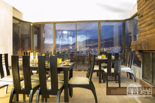 基多Hotel Bellavista Quito的一间带桌椅的用餐室和大窗户