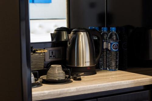 曼谷樱花天空公寓式酒店的配有盘子和瓶装水的柜台上的咖啡壶