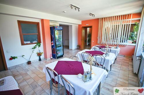 特尔古穆列什Noroc si Fericire的一间设有白色桌椅和橙色墙壁的餐厅