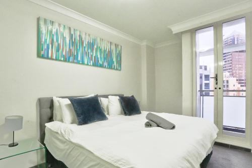 悉尼Stylish 2 Bedroom Apartment Haymarket的卧室配有带蓝色枕头的大型白色床