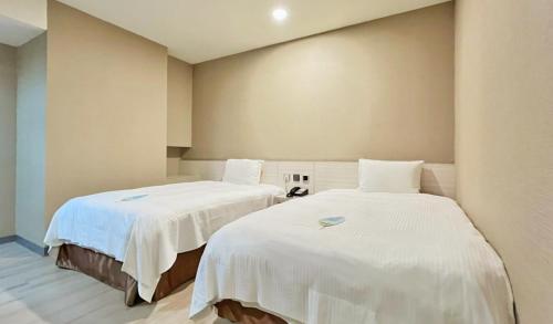 斗六市致丽伯爵酒店的配有白色床单的客房内的两张床