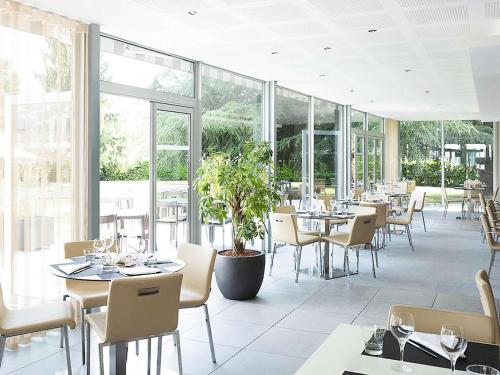 莱斯卡尔波城比利牛斯诺富特酒店的用餐室设有桌椅和窗户。
