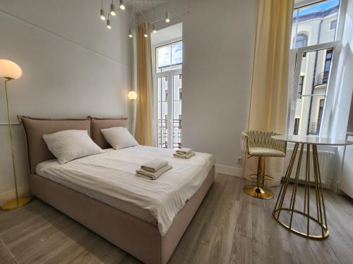 罗兹Piotrkowska.eu Apartament Romantica的卧室配有床、桌子和窗户。