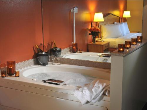 Oswego阿美瑞辛别墅和套房酒店 - 奥斯威戈的带浴缸的浴室和带蜡烛的床。