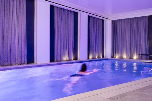 巴黎奥斯曼别墅酒店的在建筑物游泳池游泳的人