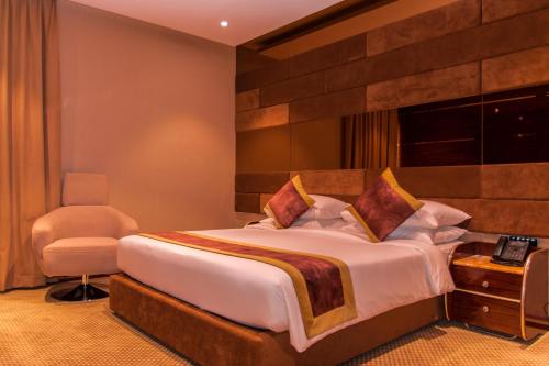 马斯喀特City Park Hotel Apartments的一间卧室配有一张大床和一把椅子