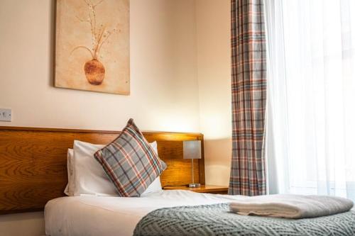 亚瑟斯通亚瑟斯敦红狮酒店的一间卧室配有一张带枕头和窗户的床