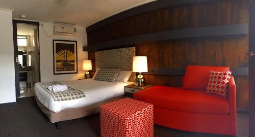 本迪戈布鲁厄姆阿慕斯酒店的一间卧室配有一张床和一张红色椅子