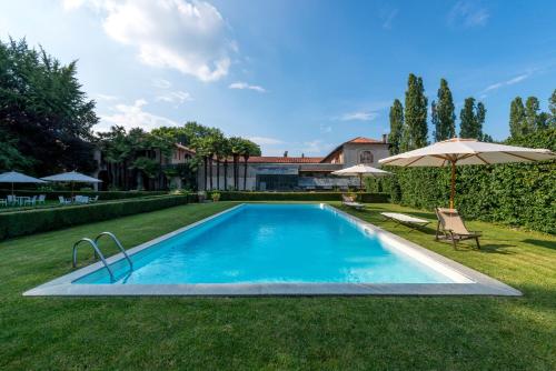 皮内罗洛Agriturismo Il Torrione的一个带遮阳伞的庭院内的游泳池