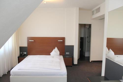 菲尔德施塔特海尔施花园酒店的卧室配有一张白色大床和木制床头板