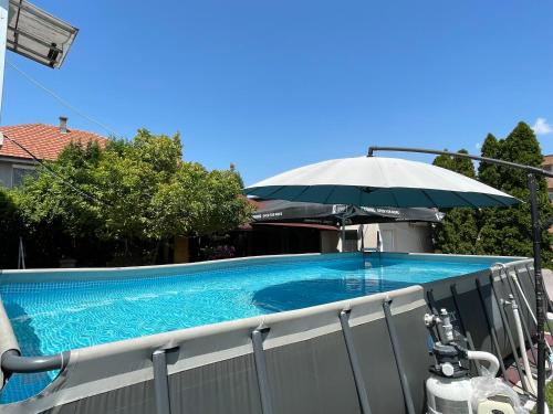 SurčinAirport Apartments Alexandra的一个带遮阳伞的游泳池和一个游泳池