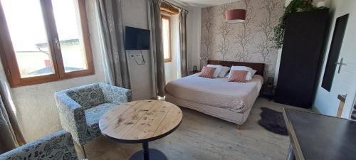 Odeillo-ViaLe Grenier des Moineaux的小房间设有一张床、一张桌子和椅子