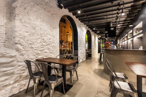 塔拉戈纳诺里亚旅馆的一间设有木桌和椅子的餐厅以及石墙