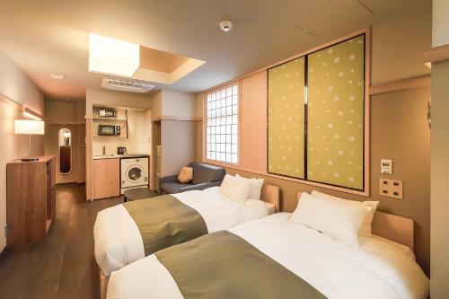 京都GOZAN HOTEL & SERVICED APARTMENT Higashiyama Sanjo的酒店客房,设有两张床和一张沙发