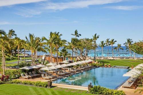 瓦克拉Mauna Lani, Auberge Resorts Collection的一个带遮阳伞和椅子的度假游泳池以及大海
