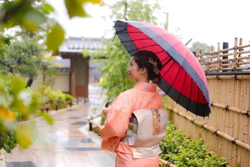 京都Kadensho, Arashiyama Onsen, Kyoto - Kyoritsu Resort的一位妇女,在雨中拿着雨伞