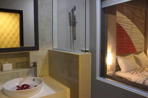 SengkuangThe Golden Bay Hotel Batam的一间带水槽和淋浴的浴室以及一张床
