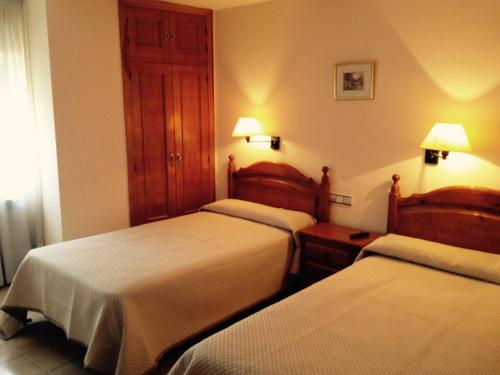 梅迪纳塞利Hostal Nicolás的酒店客房设有两张床和两盏灯。
