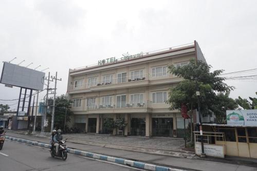 泗水Hotel Cahaya 3 Airport Juanda Surabaya的骑摩托车的人在建筑物前