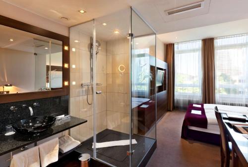 美因河畔法兰克福Flemings Selection Hotel Frankfurt-City的一间带玻璃淋浴间的浴室和一间卧室