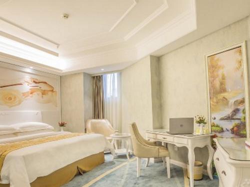 贵阳Vienna Hotel Guiyang Jiaxiulou Jichang Road的一间卧室配有一张床和一张带笔记本电脑的书桌