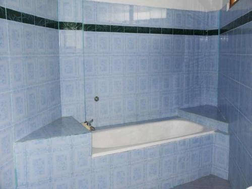 PalasariPuri Eling Blimbingsari Hotel的蓝色瓷砖浴室内的白色浴缸