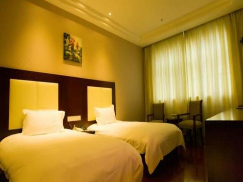 北京GreenTree Inn Beijing Daxing Xingye Street Liyuan Business Hotel的酒店客房设有两张床和一张桌子。