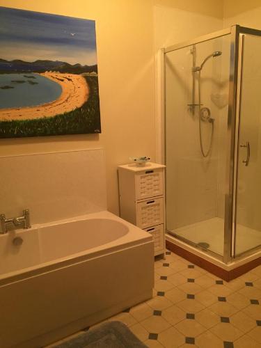 库勒Grant Arms Hotel的一间带浴缸和淋浴的浴室以及一幅画