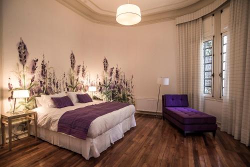 圣地亚哥玛迪尔达斯精品酒店的一间卧室配有一张大床和一张紫色椅子