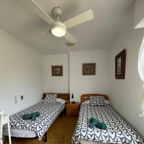 甘迪亚Habitaciones en GANDIA a 5 min del centro histórico的一间卧室配有两张床和吊扇