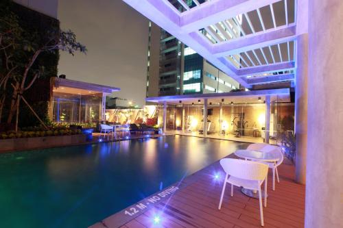 雅加达Ra Premiere Simatupang Jakarta的大楼内一个带桌椅的游泳池