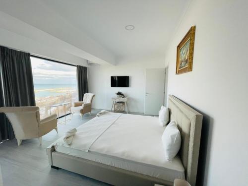 康斯坦察Maritimo Luxury ApartHotel的白色的卧室设有床和大窗户