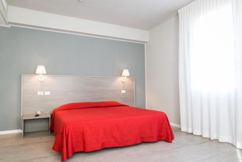 帕多瓦奥普拉托酒店的红色的床铺,位于白色的房间里,配有红色的毯子