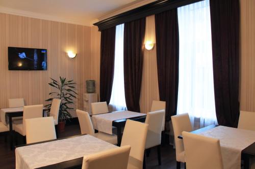 第聂伯罗Hotel Business Apartments的餐厅设有桌子、白色椅子和窗户