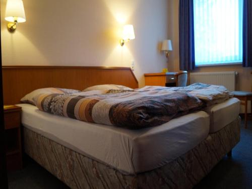 LüthorstLandhotel Wilhelm Busch的一张位于酒店客房的床铺,床上有毯子