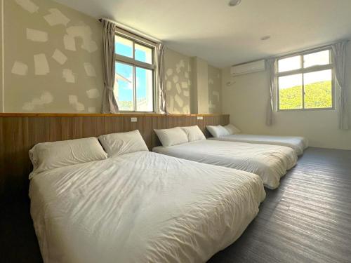 绿岛星月屋渡假山庄 的带2扇窗户的客房内的2张床