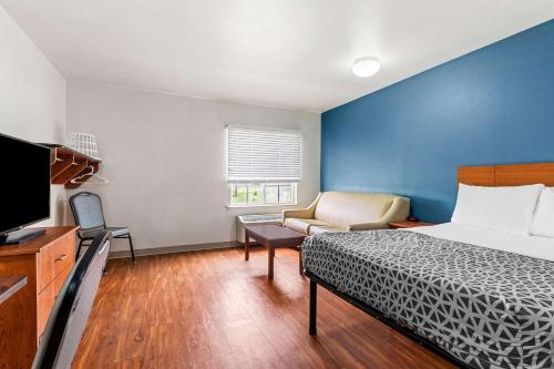 塔尔萨WoodSpring Suites Tulsa的一间卧室配有一张床、一张沙发和一台电视。