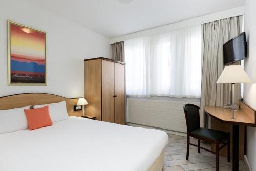 日内瓦日内瓦中心一室公寓的配有一张床和一张书桌的酒店客房