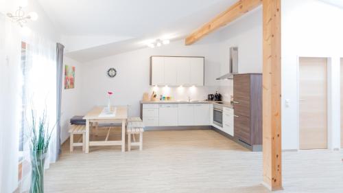 利恩茨Merlin的厨房配有白色橱柜和木桌