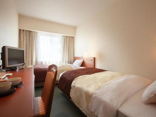 盛冈盛冈珍珠城市饭店的酒店客房设有两张床、一张桌子和一台电视。