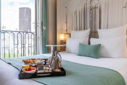 巴黎巴黎蒙帕纳斯拉斯帕伊美居酒店的一间酒店客房,床上放着一盘食物